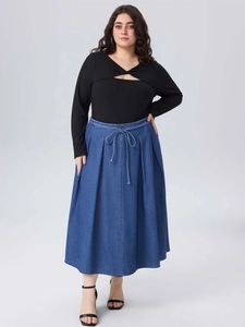 Women's plus size long sleeve top with cutout knot and a navy blue pleated denim skirt