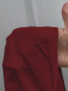 Close-up of the fine ribbed texture and shoulder seam on a dark red knit t-shirt