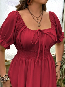 Détail de la taille smockée et du col carré sur cette robe d'été rouge à manches bouffantes