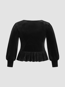 Macro detail of black velvet texture with peplum hem and puff sleeves on long sleeve top