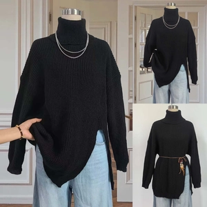 Close-up of black oversized turtleneck sweater featuring side slits and chunky knit texture