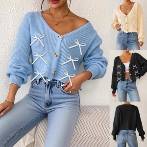 Détail du cardigan en maille avec col en V, nœuds en ruban et boutons marbrés