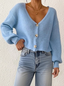Détail d'un cardigan en grosse maille bleu clair avec col en V et boutons en écaille