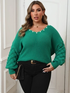 Detail of green V-neck sweater featuring pearl embellishments and diamond textured sleeves