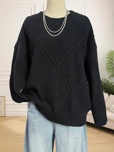 Detailed view of black diamond-pattern knit sweater with ribbed cuffs and hem texture