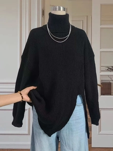 Detailed view of black chunky knit turtleneck sweater featuring side slit and ribbed texture