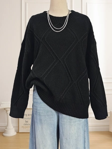 Detailed close-up of black diamond pattern knit sweater with textured weave and round neck