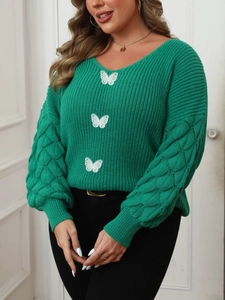 Detail of green V-neck knit sweater featuring white butterfly embroidery and hollow sleeves