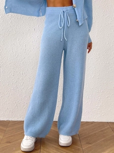 Detailed close-up of light blue knitted high waist trousers with functional drawstring waist