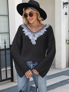 Detailed close-up of silver wing embroidery on black V-neck sweater for women