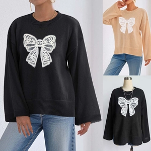 Detailed view of women's round neck knit sweater with large white lace bow applique