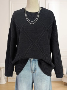 Macro shot of the black knit sweater featuring 3D diamond texture and crew neckline