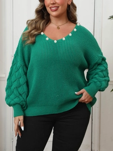 Detailed close-up of green oversized V-neck sweater with knit texture and pearl details