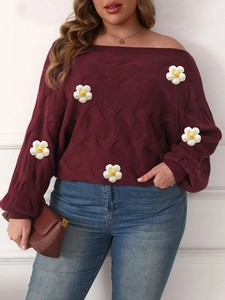 Detail view of burgundy chunky knit sweater with textured cable pattern and floral patches