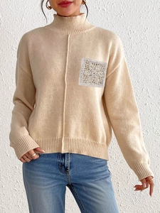 Detailed view of the intricate lace crochet patch on a beige turtleneck knit sweater
