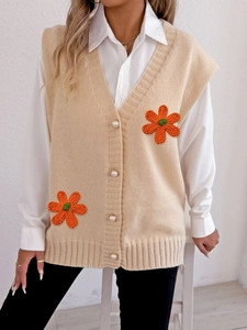 Détails du gilet en maille beige avec boutons perles et écussons floraux orange