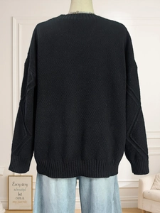 Back view of women's black cable knit sweater featuring a relaxed fit and ribbed cuffs