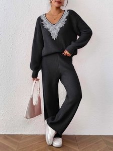 Detailed view of black knit sweater V-neckline with silver sequin wing embroidery