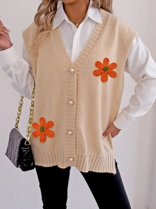 Détail du gilet en tricot avec boutons perlés et application de fleur au crochet orange