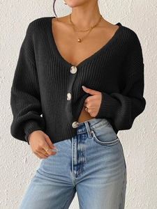 Gros plan détaillé d'un cardigan noir en grosse maille avec des boutons effet marbre et col V