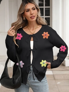 Detail of black knit cardigan with tie-front closure and colorful crochet flower patches