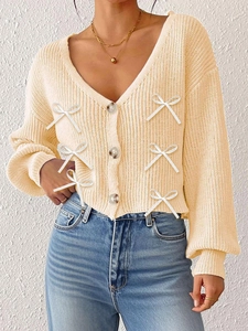 Détail d'un cardigan en maille à col en V avec boutons marbrés et nœuds blancs