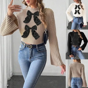 Detail view of cropped sweater showing turtleneck, flare sleeves, and dual black bows