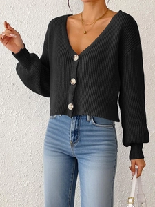 Gros plan d'un gilet en maille noire avec col en V et boutons aspect marbre