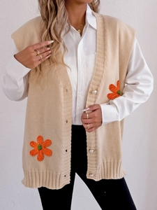 Détail du gilet en maille beige avec boutons en perles et appliques de fleurs au crochet