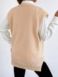 Beige knitted vest with pearl buttons and side slits layered over white shirt