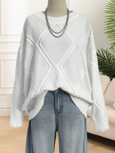 Detailed close-up of white cable knit sweater with classic diamond texture and crew neck