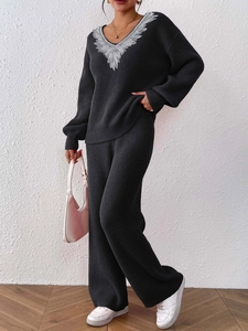 Detail of V-neck knit sweater with white floral lace trim and wide-leg trousers