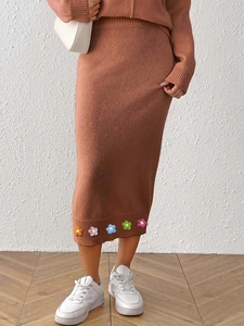 Detail of terracotta knit set featuring colorful 3D crochet flowers on the midi skirt