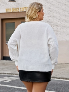Detail of white oversized knit sweater featuring intricate cable knit sleeves in street style