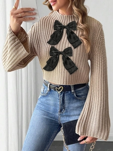 Detail of khaki chunky knit cropped sweater with oversized black bows and bell sleeves