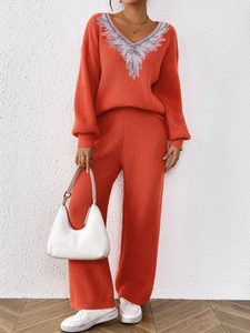 Detail of orange V-neck knit sweater featuring silver feather embroidery on the neckline
