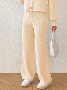Detail of beige knit set featuring buttoned cardigan and drawstring wide-leg pants