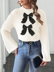 Detail of cream knit sweater featuring large black satin bows and ribbed texture