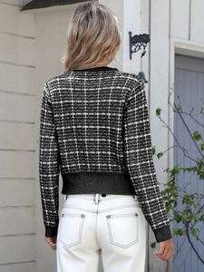 Macro view of plaid knit cardigan featuring ribbed cuffs and classic textured pattern