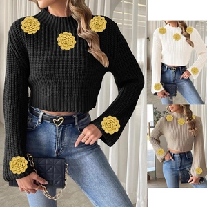 Detail of crochet flower appliqués on the shoulders and bell sleeves of this knit sweater