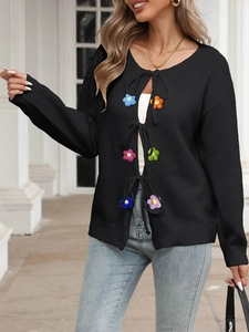 Dettaglio di cardigan nero in maglia con scollo a V e fiori colorati lavorati a maglia