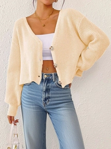 Gros plan sur un cardigan en maille beige avec de gros boutons marron et texture