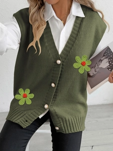 Détail du gilet en tricot vert avec boutons en nacre et broderie de fleurs en 3D