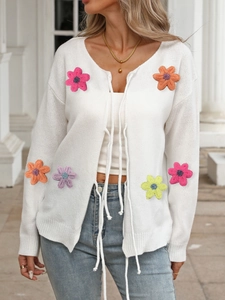 White knit cardigan with colorful 3D crochet flowers and front bow ties outdoors