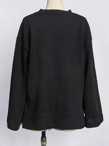 Close-up of black knit sweater featuring ribbed cuffs and detailed floral embroidery