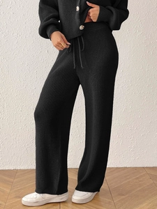 Detailed view of black knitted set featuring vertical texture, amber buttons, and drawstring