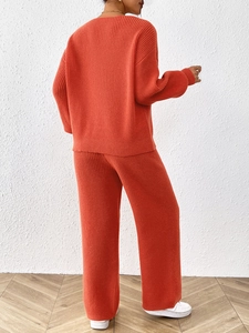 Women's orange knit set featuring a long sleeve sweater and wide leg trousers from back view
