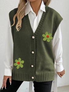 Détail du gilet en maille vert foncé avec boutons perlés et fleurs crochetées en 3D