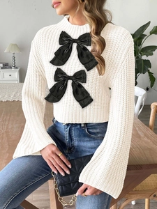 Women's cropped cable knit sweater with flared sleeves and black decorative bows