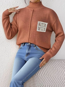 Close-up of rust red knit sweater featuring half-turtleneck and white lace patch detail
